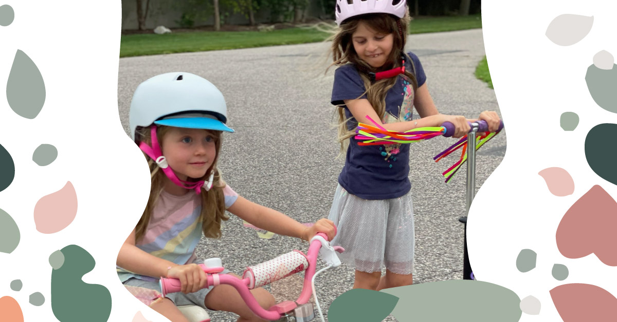 two girls playing outside on children's bikes wearing safety gear
